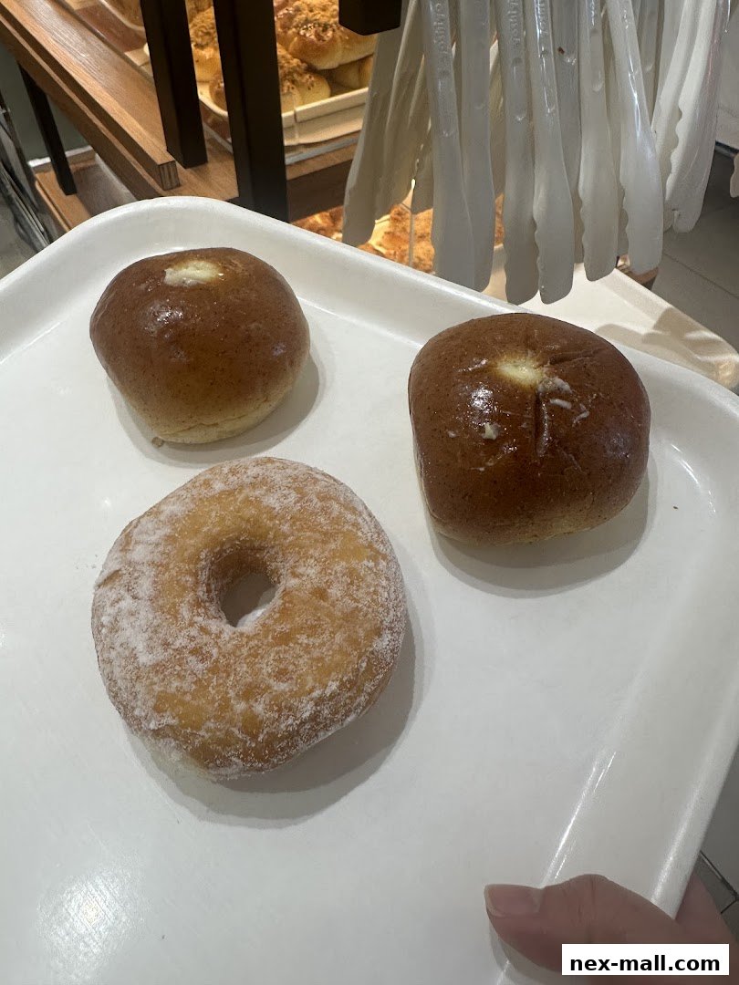 A tray holds a sugar-dusted donut and two buttered buns from Four Leaves bakery.