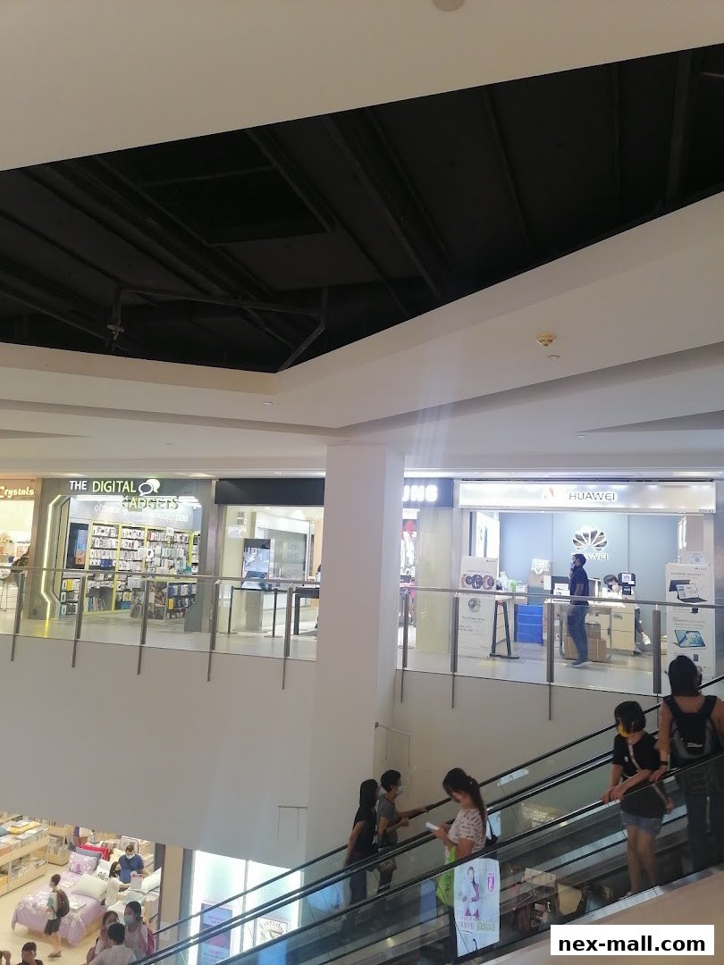 People on escalators in a mall with shops like Huawei and The Digital Gadgets visible.