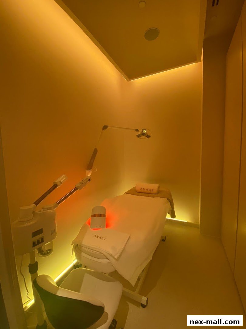 A treatment room with a massage bed, facial steamer, and LED mask.