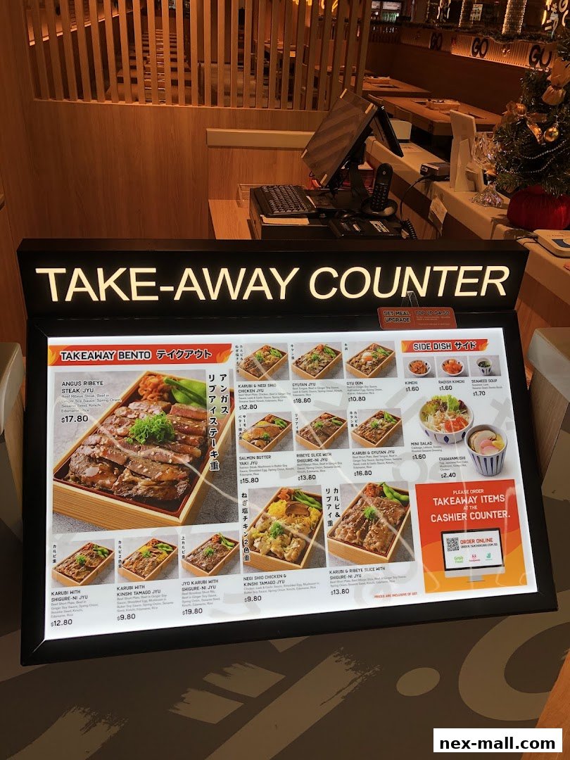 A brightly lit menu board displaying various Japanese bento boxes and side dishes for takeaway.