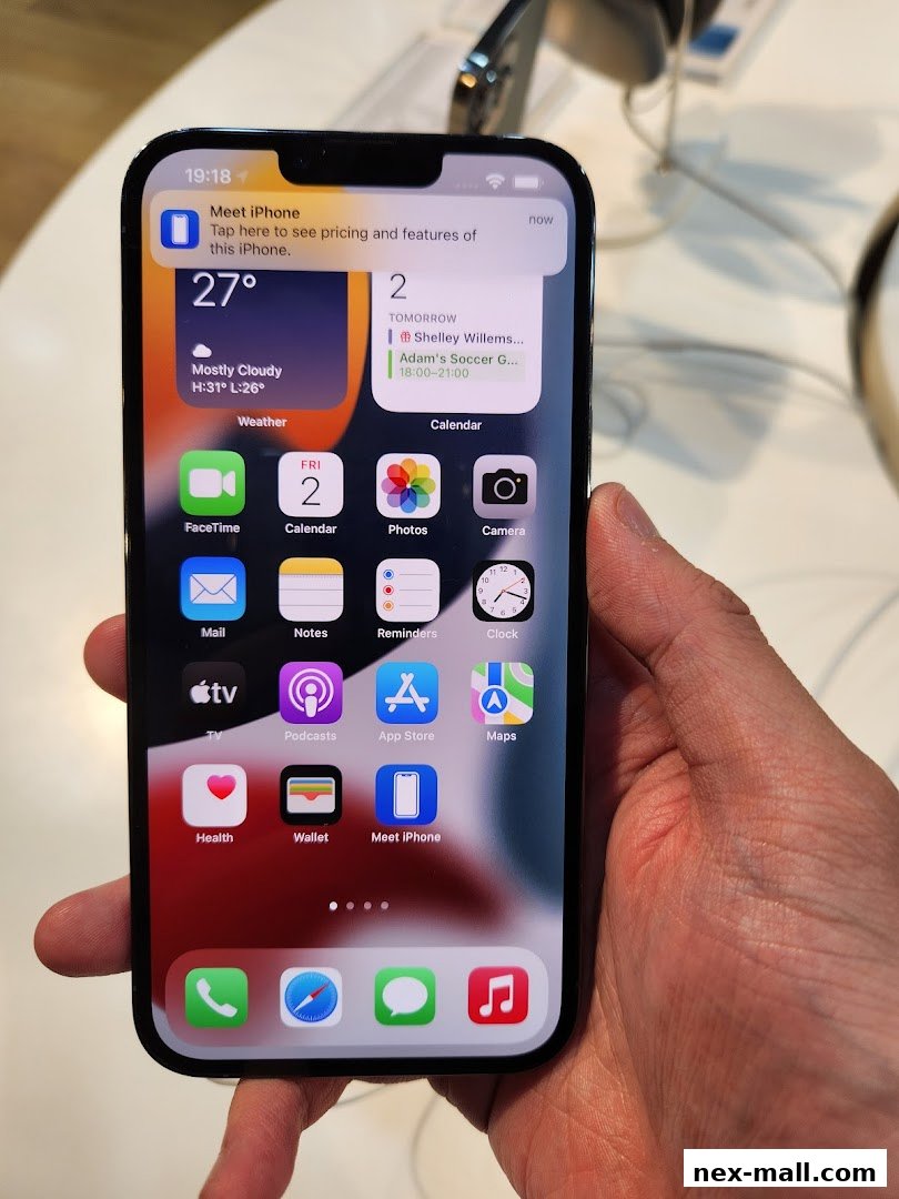 A hand holds an iPhone displaying the home screen with various app icons and widgets.