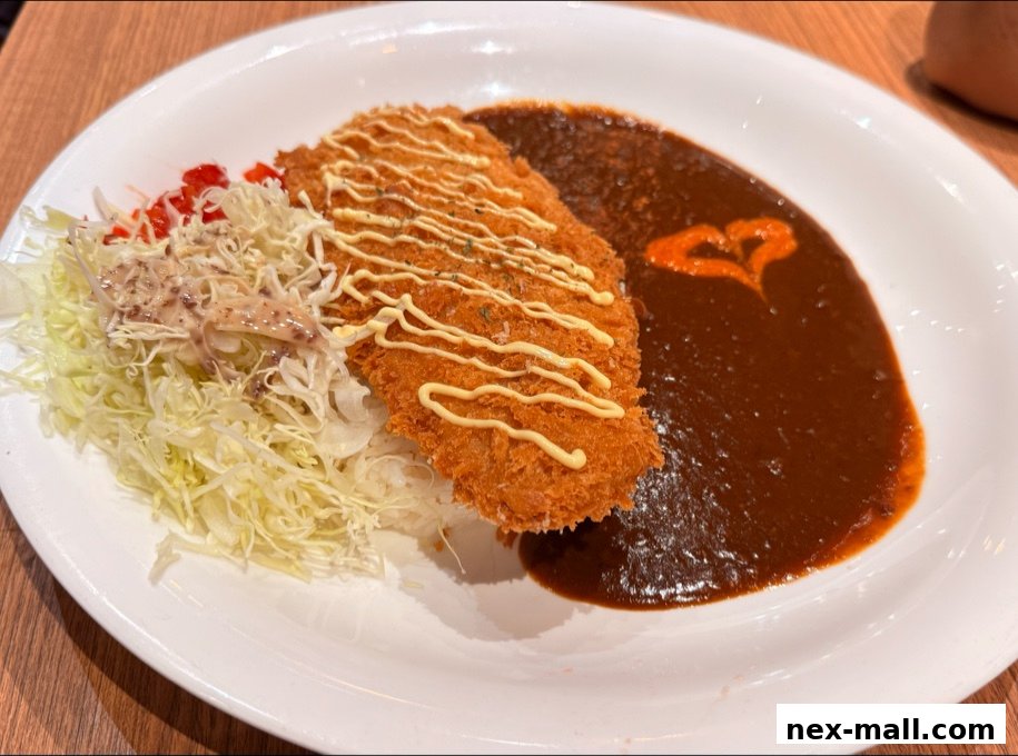A plate of Japanese curry with a crispy cutlet, shredded cabbage, and a heart-shaped garnish.