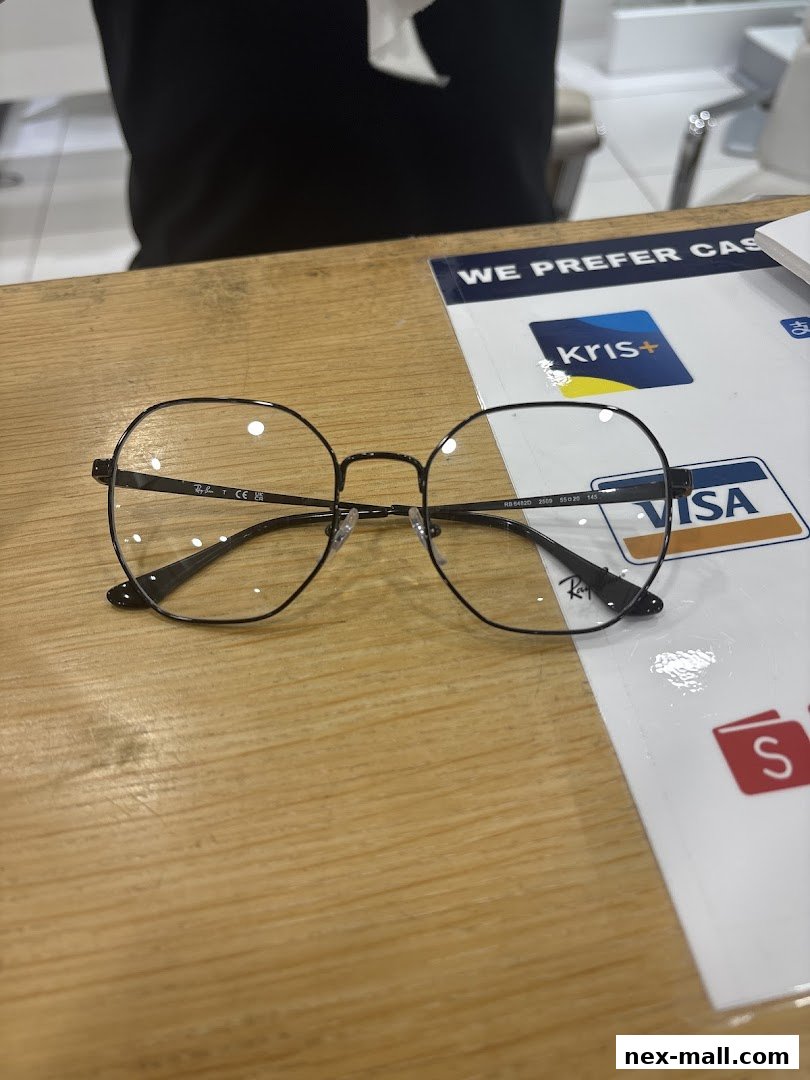 A pair of stylish black Ray-Ban glasses rests on a wooden counter next to payment method signs.