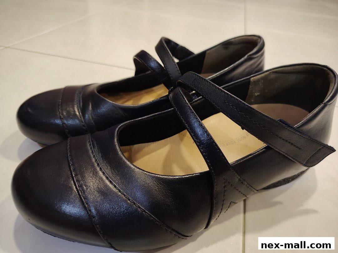 A pair of black leather Mary Jane shoes with strap closures.