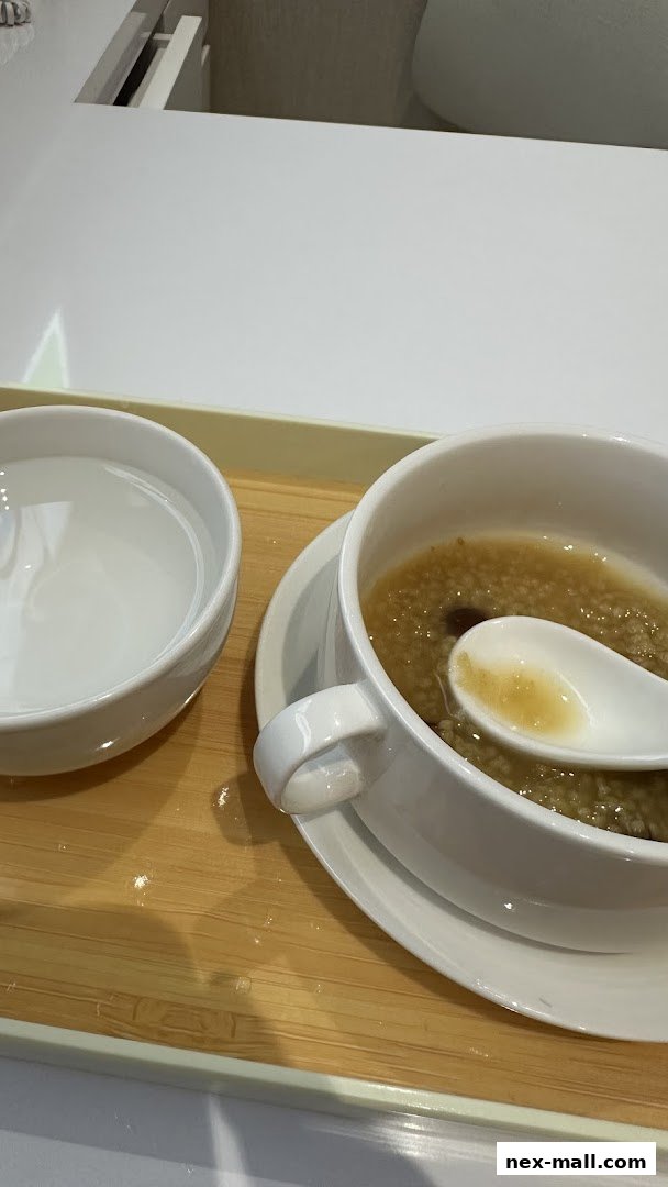 A bowl of porridge with a spoon and a glass of water on a wooden tray.