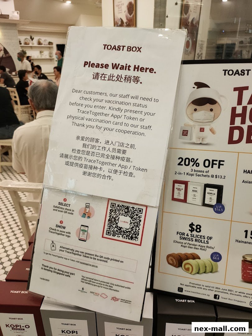 A sign at Toast Box NEX informs customers about vaccination status checks before entry.