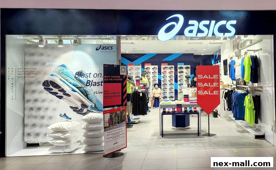 The exterior of an ASICS store showcasing athletic shoes and apparel, with sale signs.