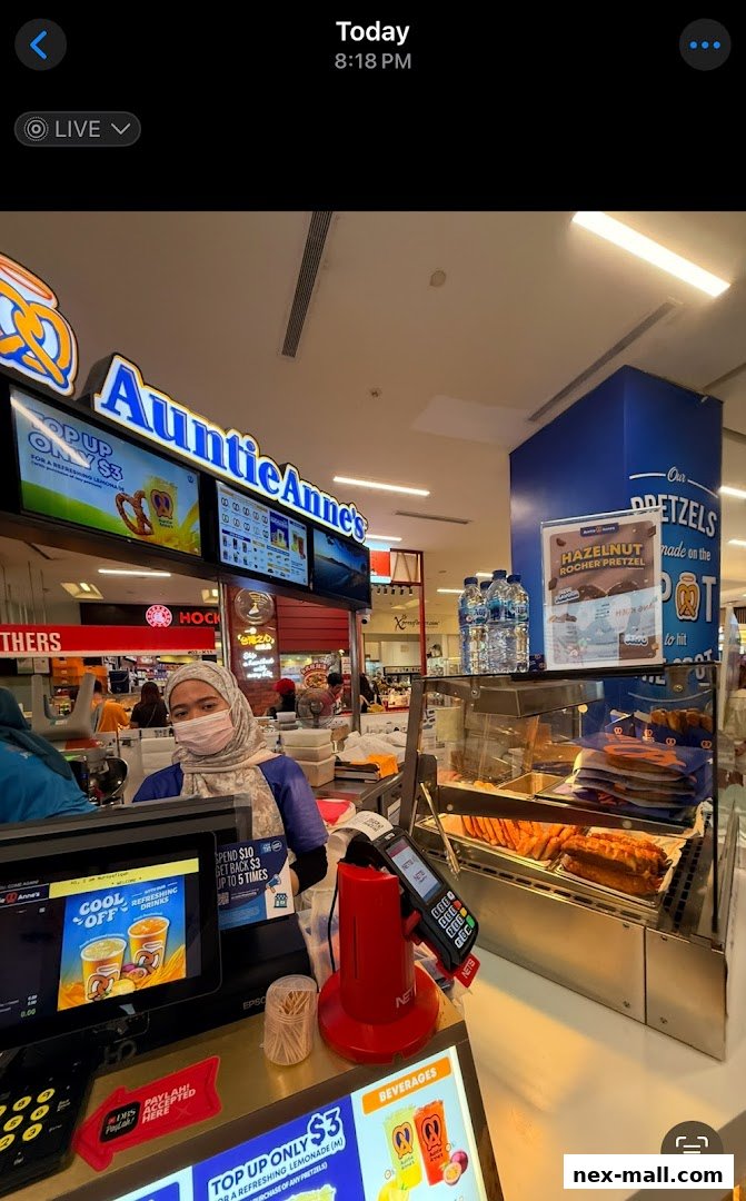 Auntie Anne's pretzel shop counter with a staff member and display of pretzels.
