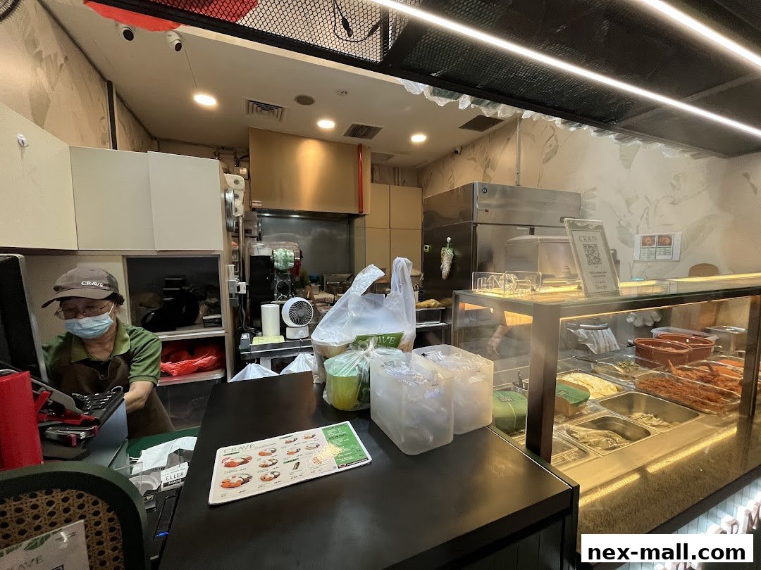 A person wearing a mask and cap works behind a counter at Crave Nasi Lemak.