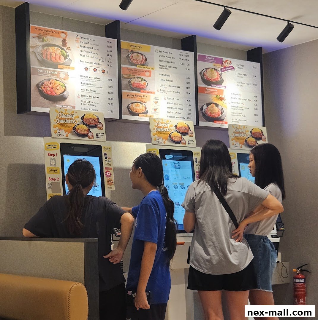 Customers ordering food at self-service kiosks with digital menus displayed above.
