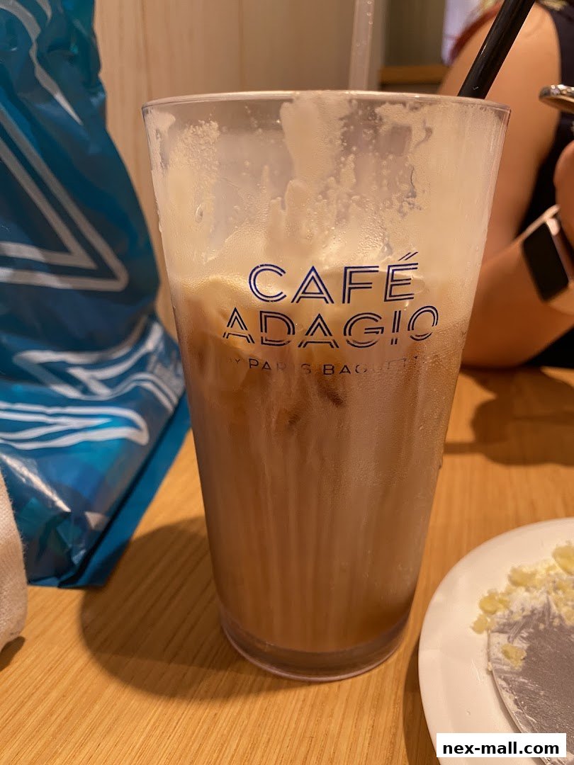 A close-up of an iced coffee drink with 'CAFÉ ADAGIO' logo on the cup.