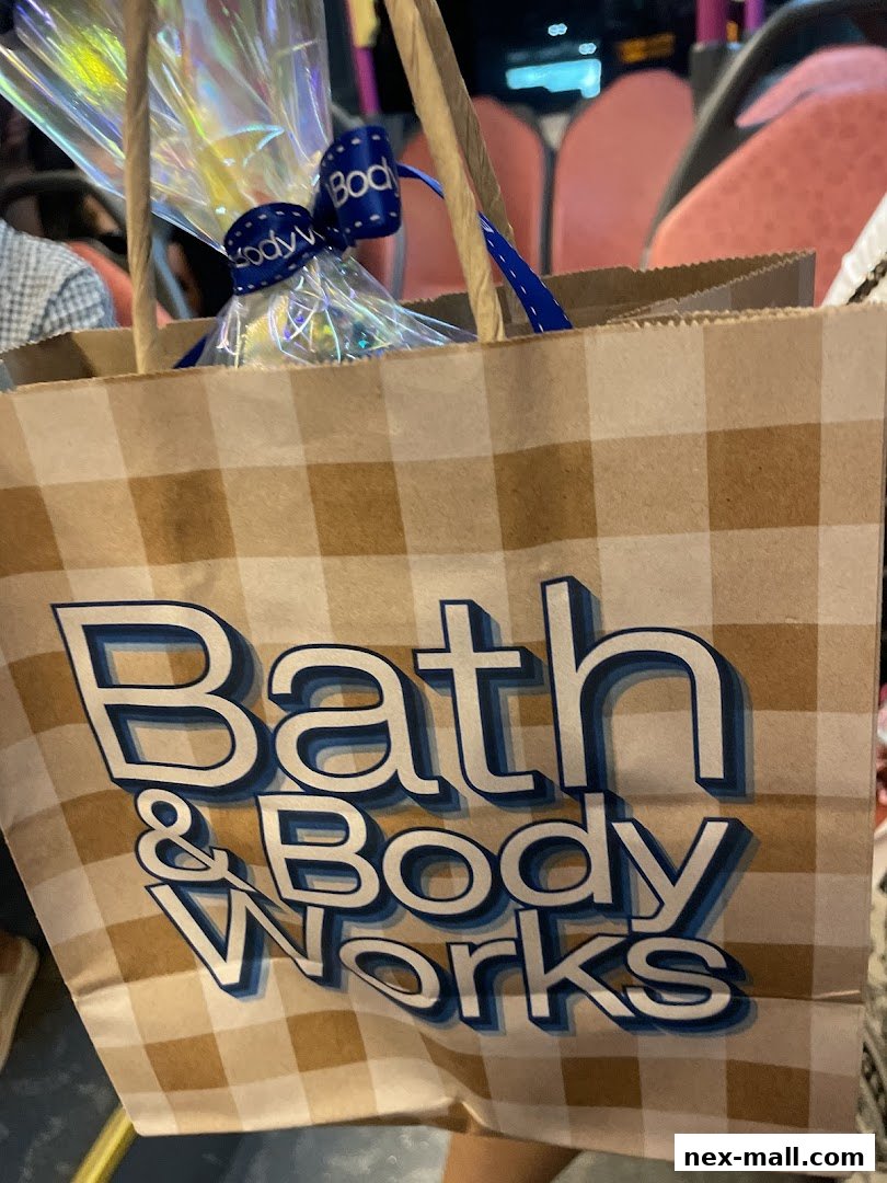 A Bath & Body Works shopping bag with a gift inside, tied with a blue ribbon.