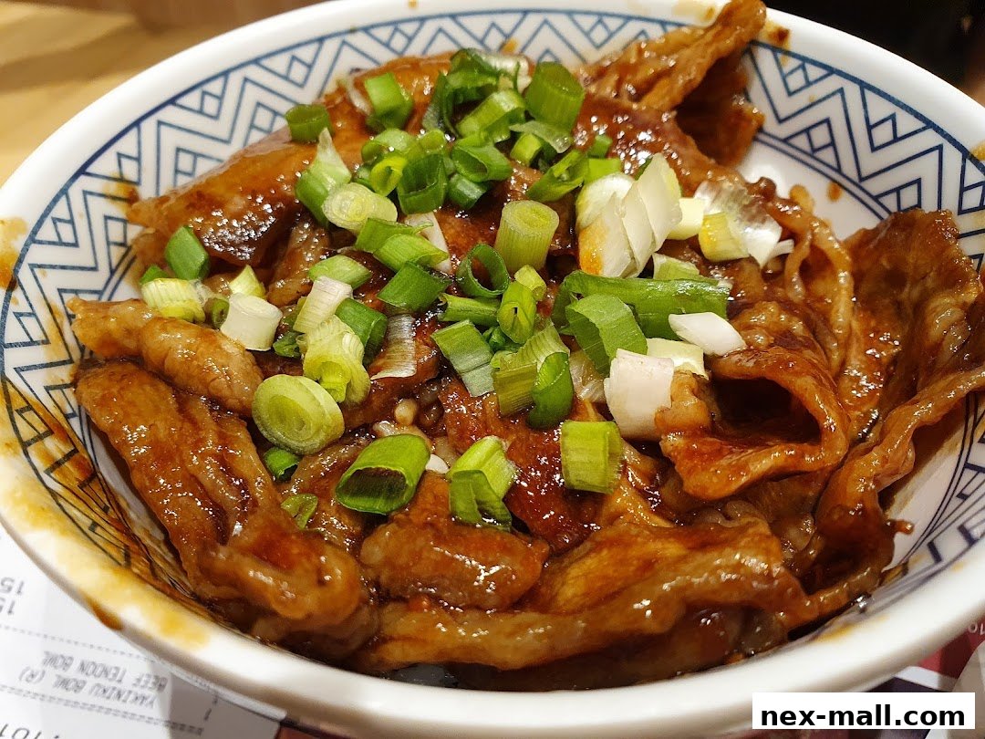 A close-up of a Yoshinoya beef bowl topped with chopped green onions.