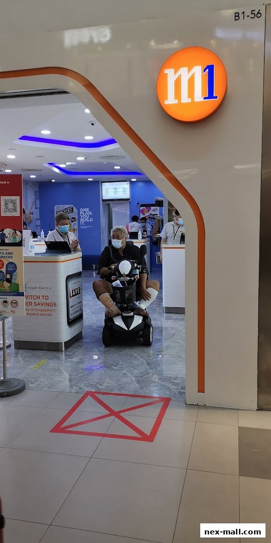 Entrance to an M1 phone shop with a customer on a mobility scooter.