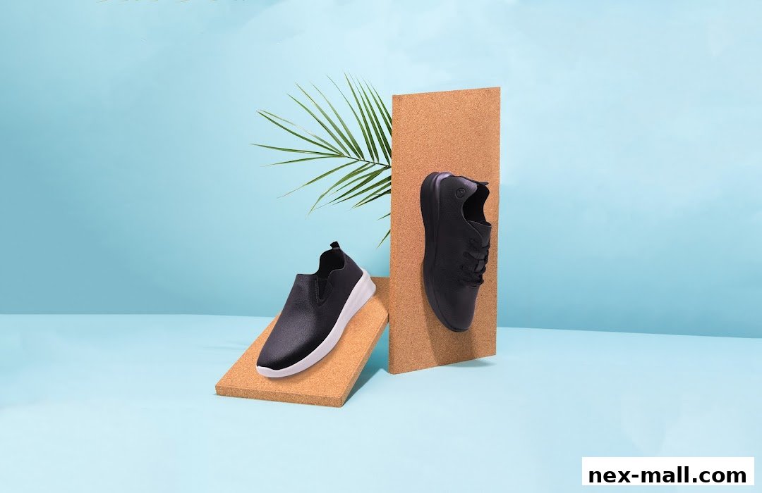 Two black shoes, one slip-on and one lace-up, displayed with palm leaves and cork boards.