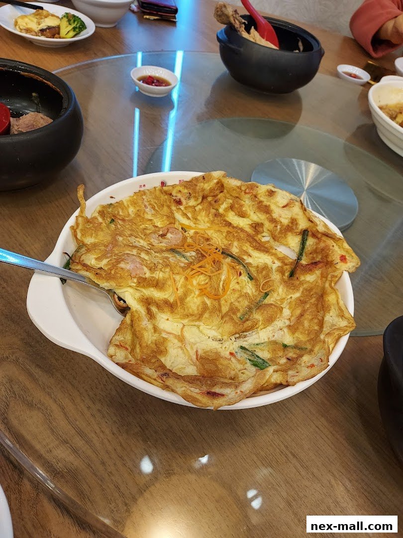 A close-up of a golden omelet with vegetables served on a white oval dish.