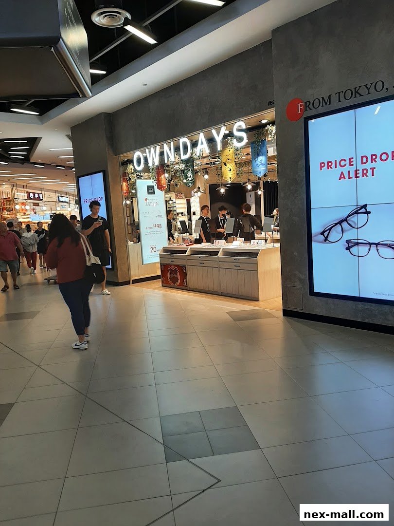 The OWNDAYS shop front with a "Price Drop Alert" displayed on a screen.
