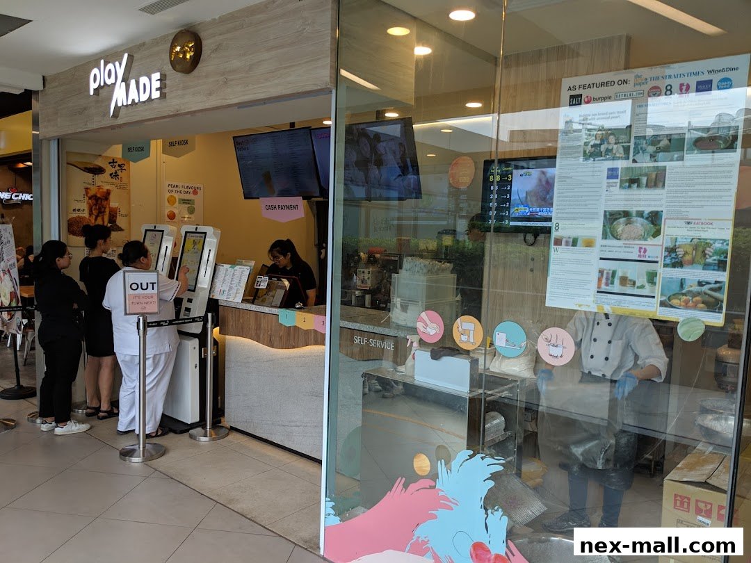 PlayMade shop front with customers ordering at self-service kiosks and staff behind the counter.