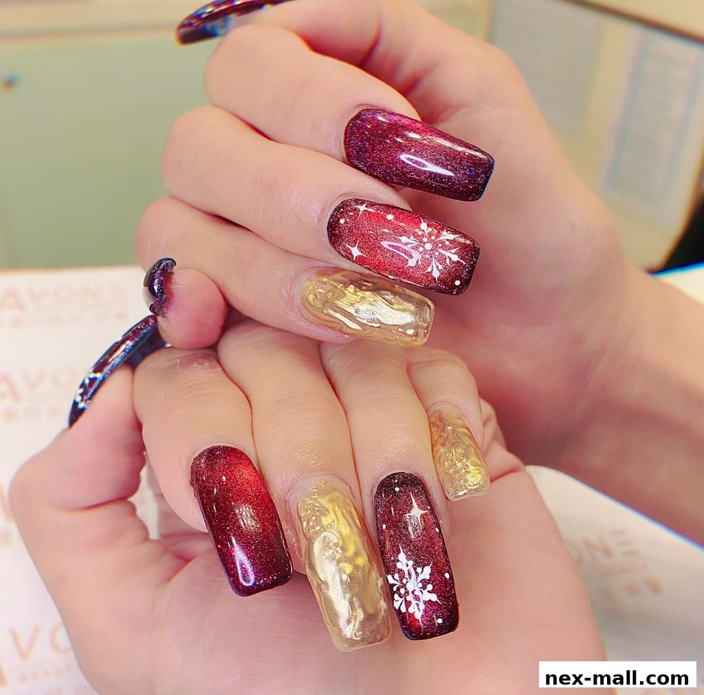 Close-up of hands with festive red, gold, and snowflake-themed nail art.