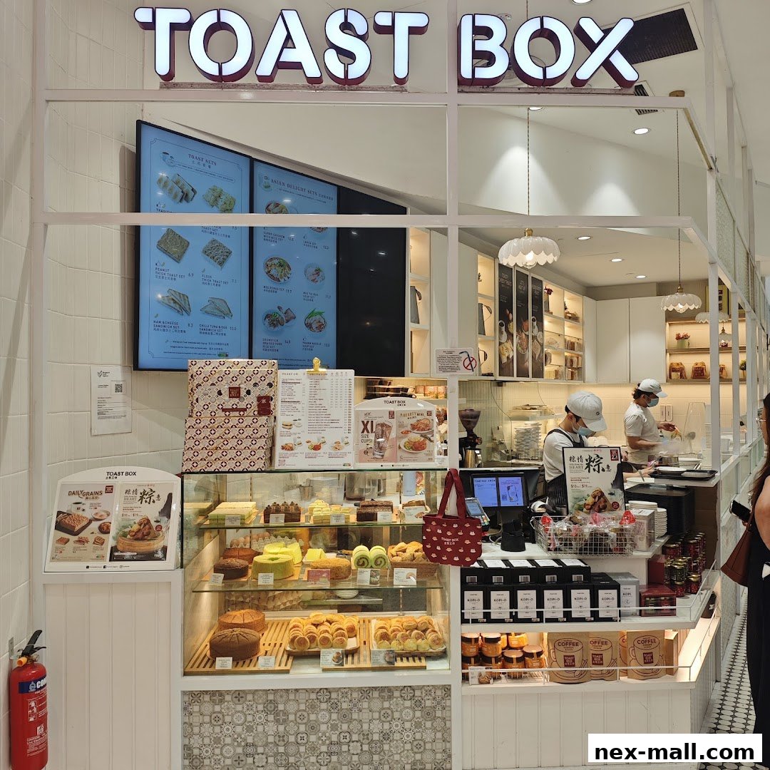 The Toast Box NEX shop front displays a variety of pastries, drinks, and menu boards.