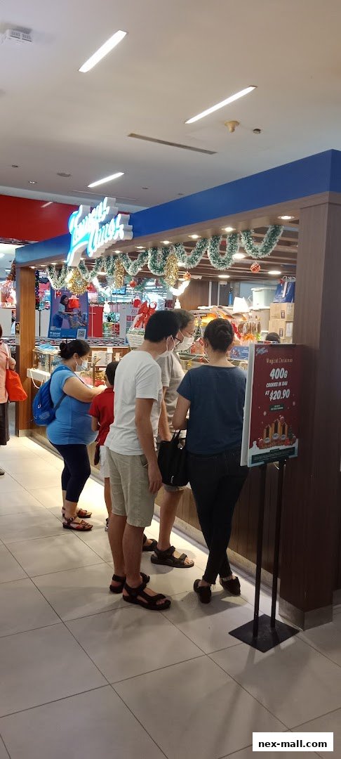 People queuing at a Famous Amos cookie store decorated with Christmas garlands.