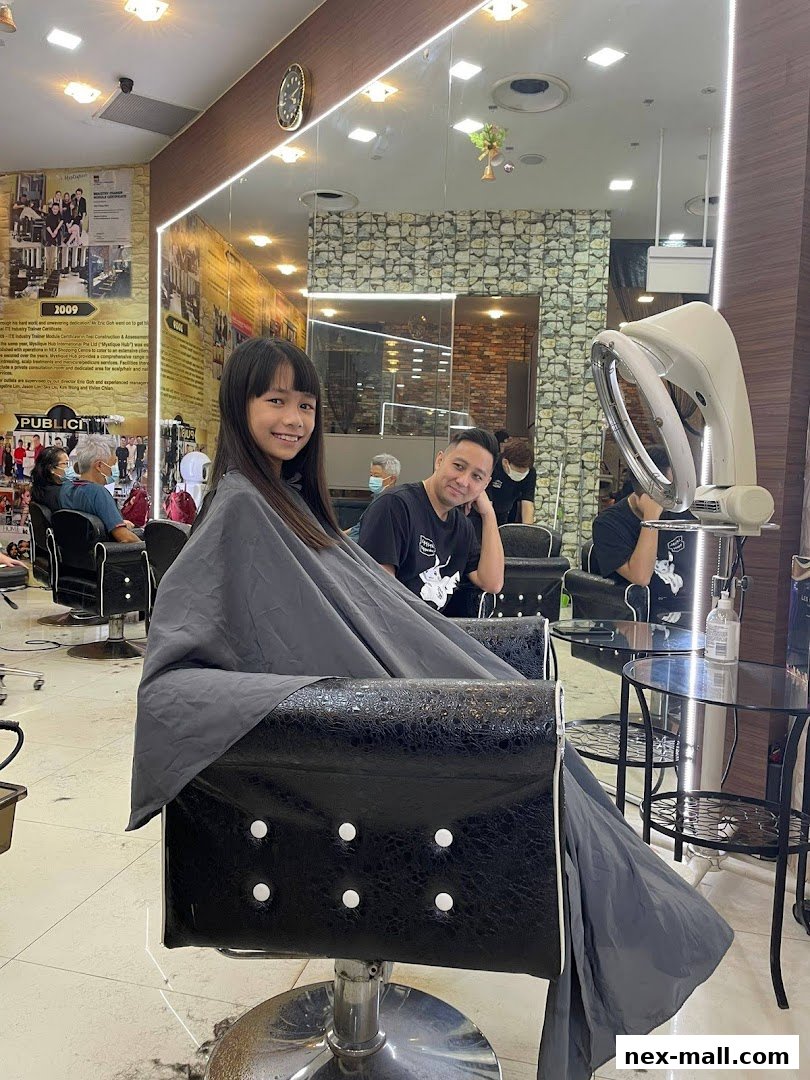 A young girl smiles while sitting in a salon chair, ready for a haircut.