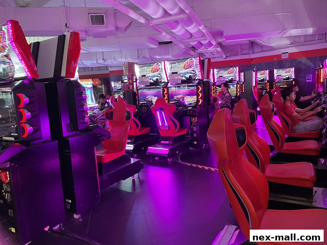 Interior of an arcade with racing game simulators and people playing.