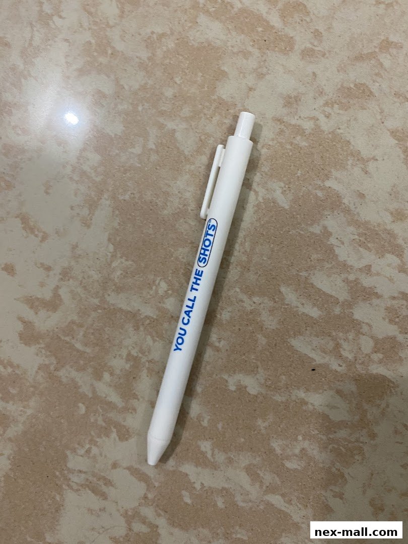 A white pen with blue text that says 'YOU CALL THE SHOTS' on a marble-patterned surface.