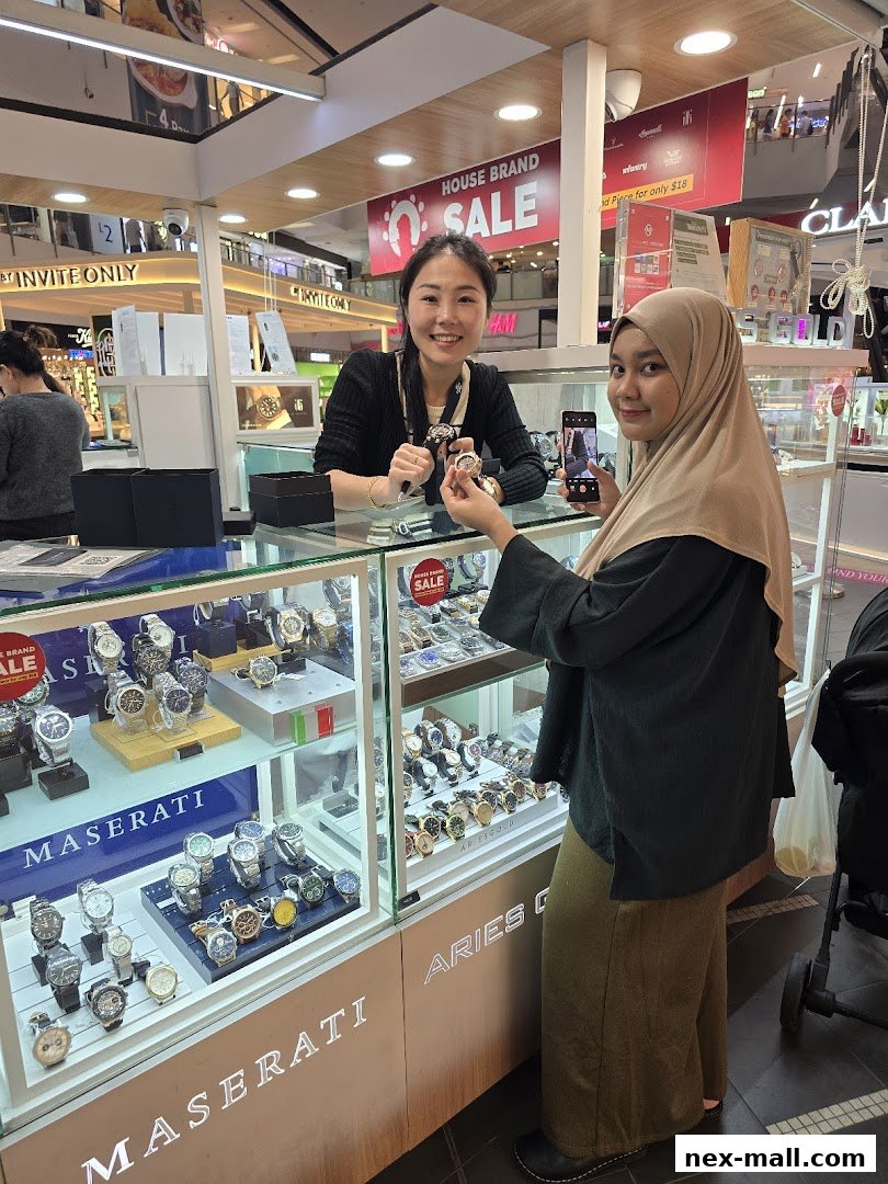 A shop assistant shows watches to a customer in a well-lit timepiece store.