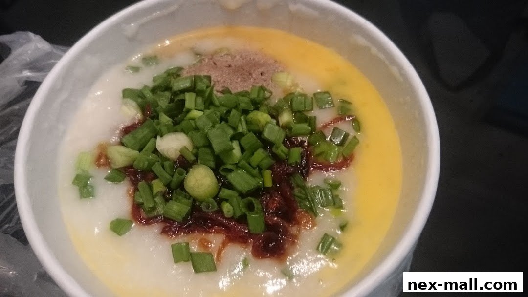 A close-up of a bowl of congee topped with chopped scallions, chili oil, and a raw egg yolk.