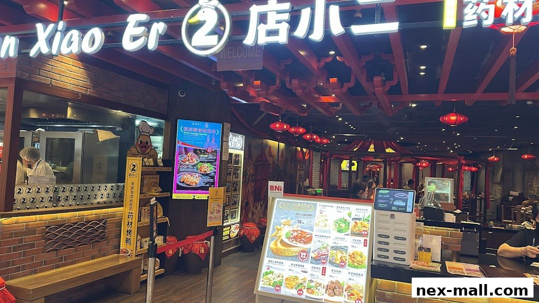 The entrance of Dian Xiao Er NEX restaurant with a prominent sign and menu displays.