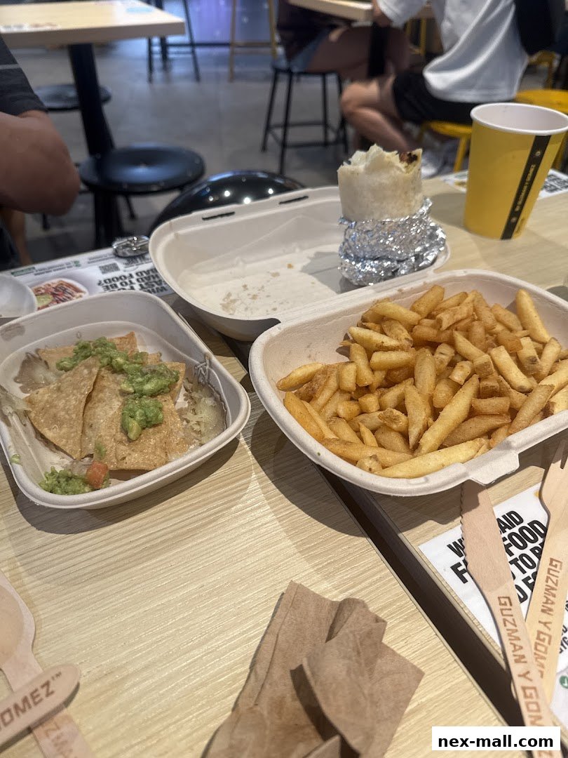 A table with a burrito, fries, and nachos from Guzman y Gomez.