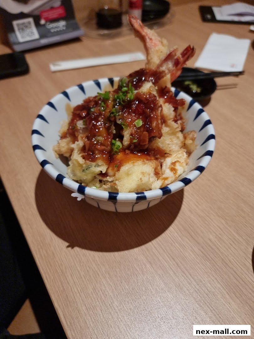 A close-up of a delicious tempura bowl with shrimp and sauce, garnished with green onions.