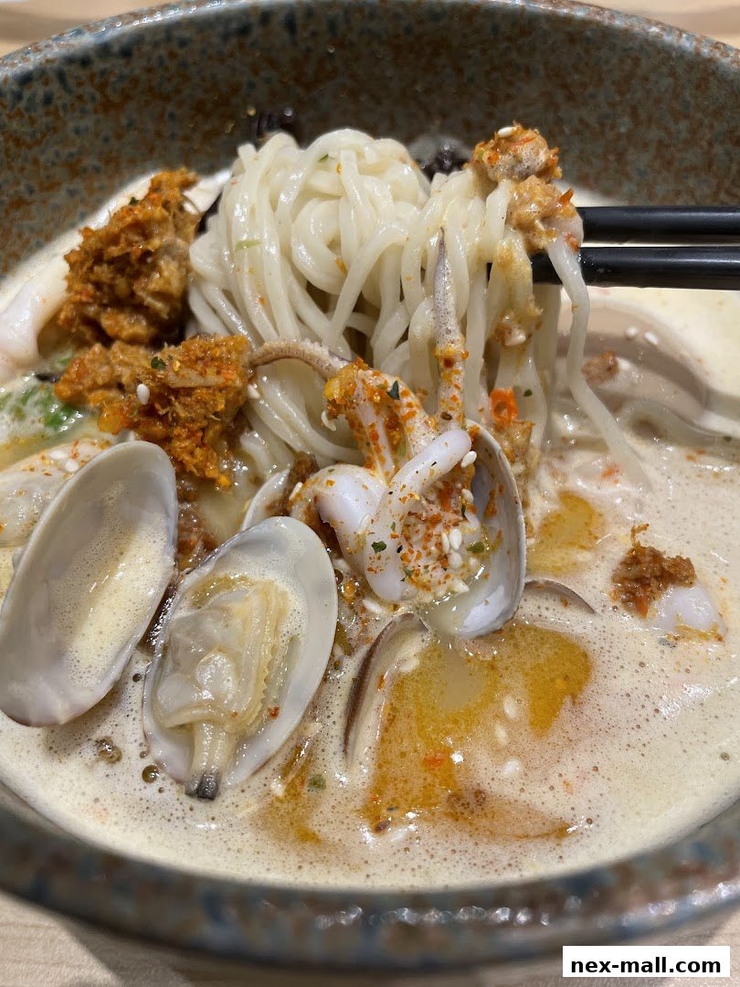 A close-up shot of a steaming bowl of ramen with noodles, clams, and squid.