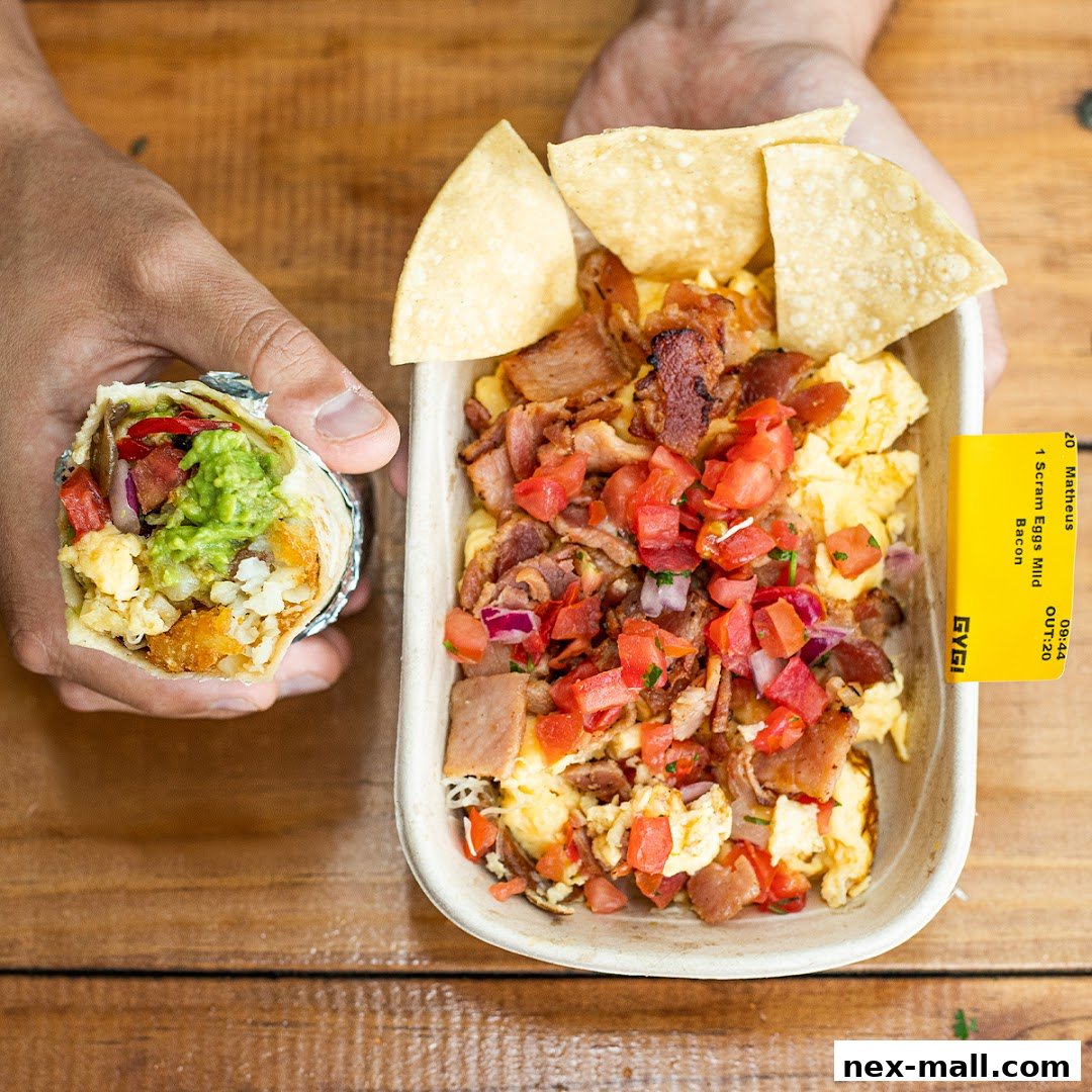 A person holds a burrito next to a bowl of scrambled eggs with bacon and salsa.