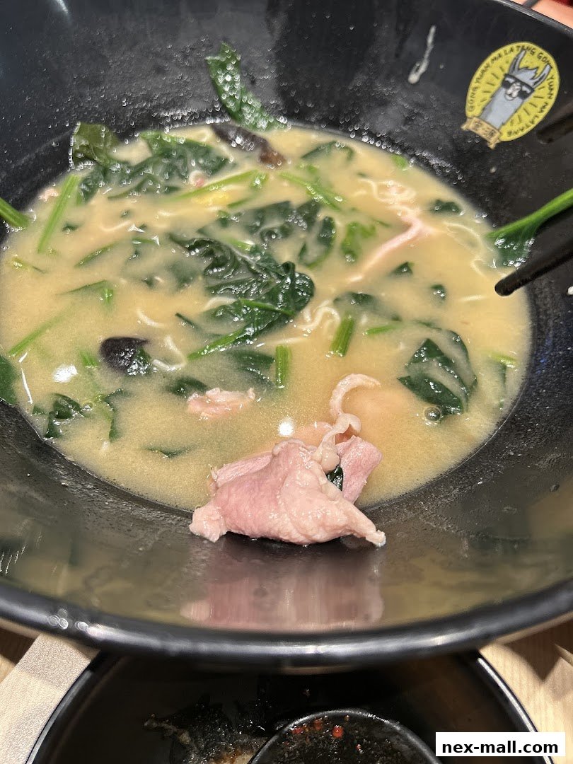 A close-up of a bowl of Mala Tang with spinach, thinly sliced meat, and noodles.