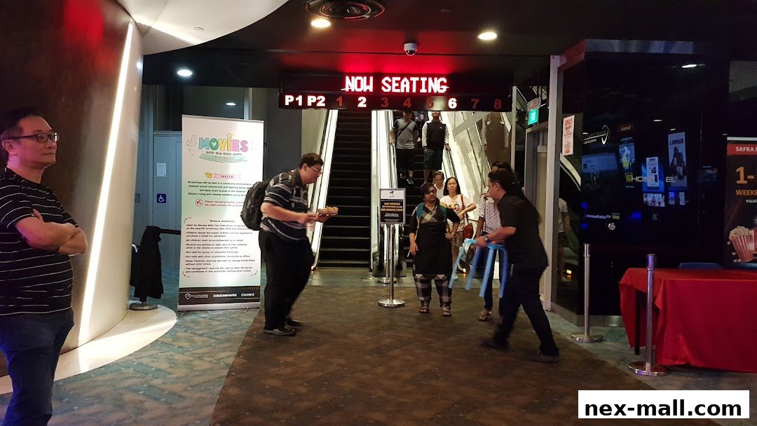 People are queuing for movie seats at Shaw Theatres NEX with a 'Now Seating' sign.