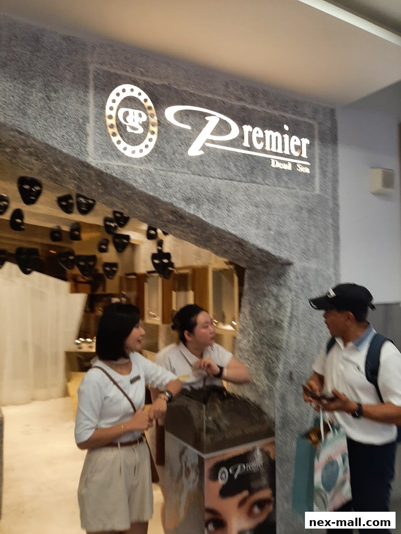People interacting outside a Premier Dead Sea store with a prominent illuminated sign.