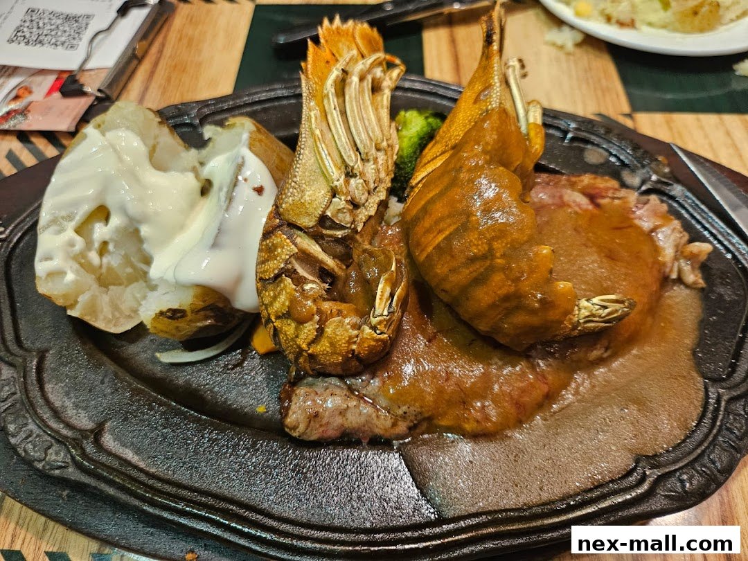 A sizzling steak and lobster dish served with a baked potato and gravy.