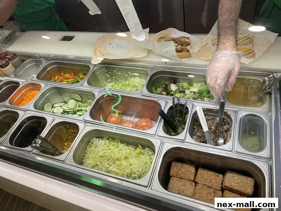 A Subway employee prepares a sandwich with fresh ingredients and toppings.