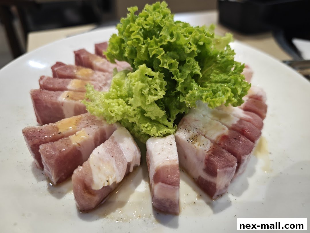 A plate of thinly sliced raw pork belly with a side of fresh green lettuce.