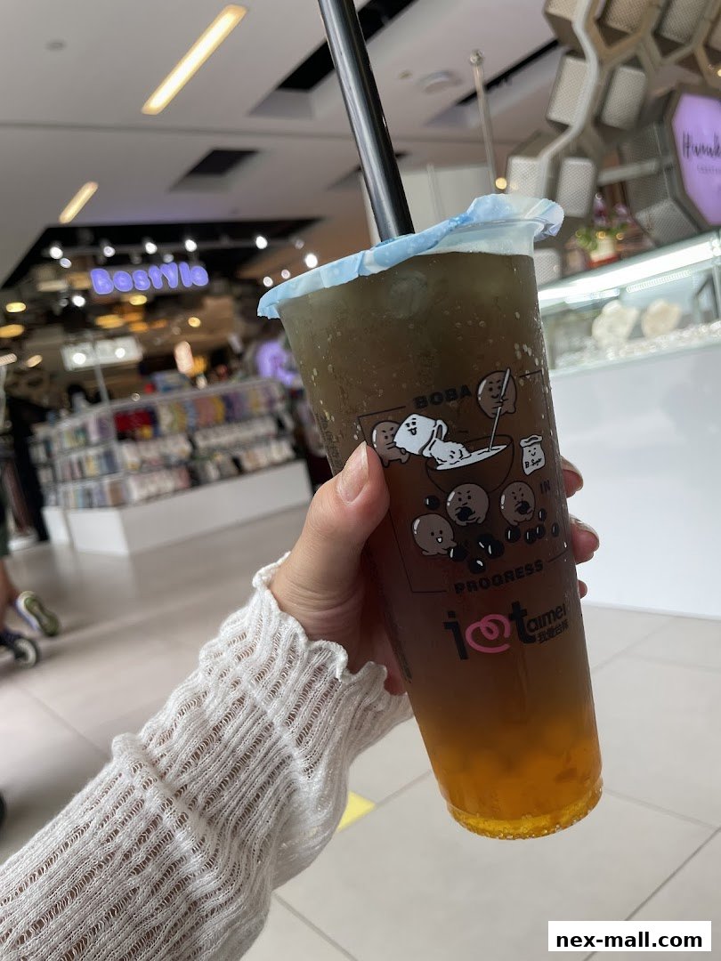 A hand holds a refreshing boba tea from I Love Taimei in a shopping mall.