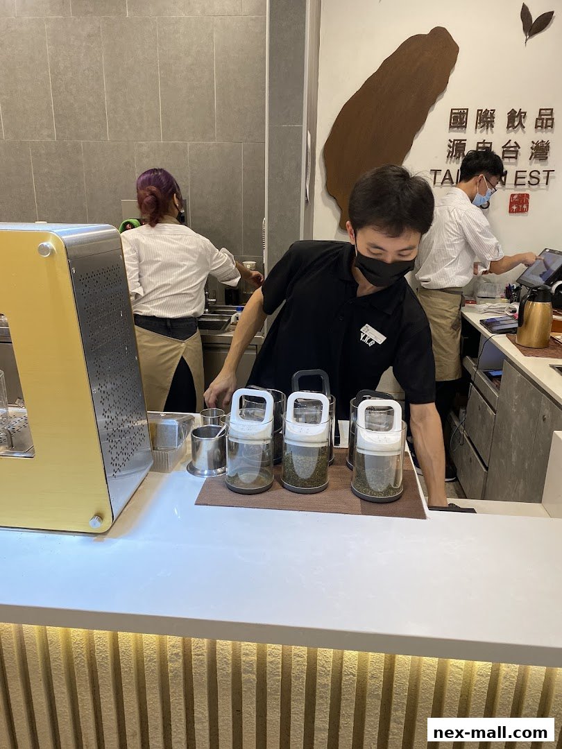 Staff preparing drinks behind a counter with tea ingredients and a cash register.