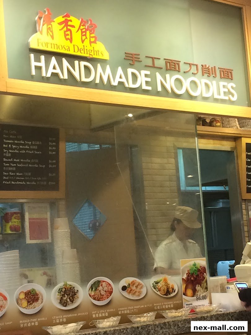 A food stall with a menu board and various noodle dishes displayed.