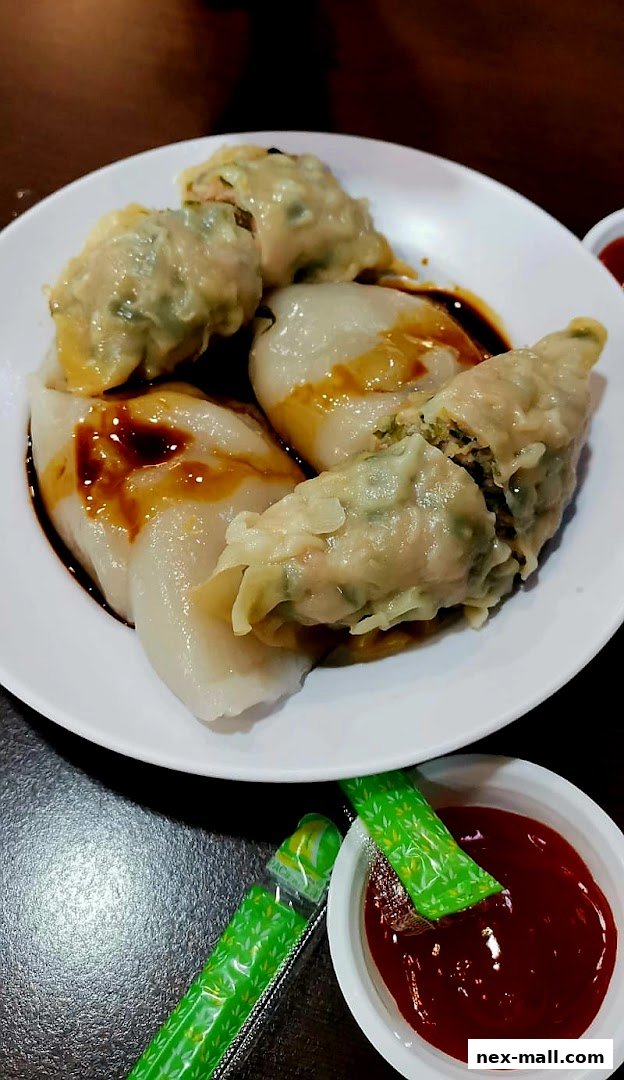 A plate of steamed dumplings with soy sauce and a side of ketchup.