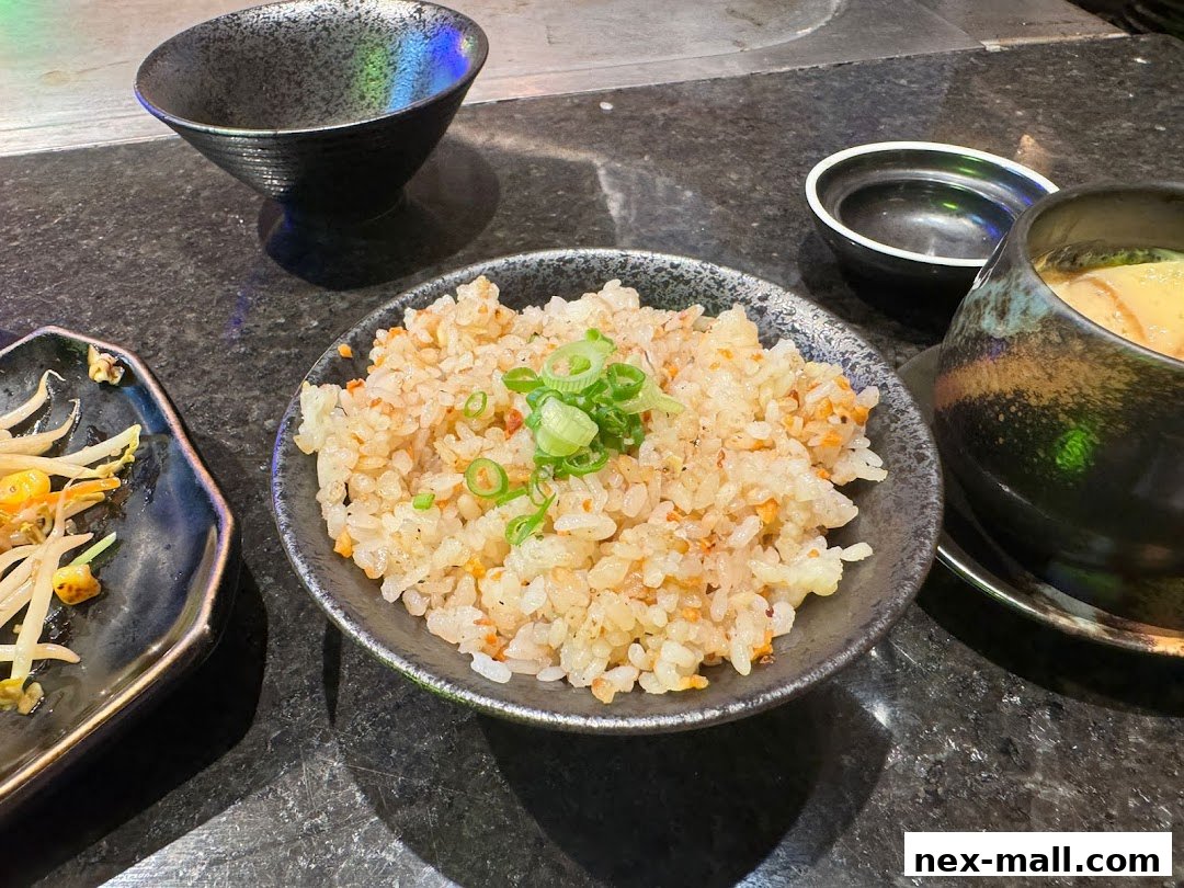A close-up of a bowl of fried rice with green onions, next to other dishes.