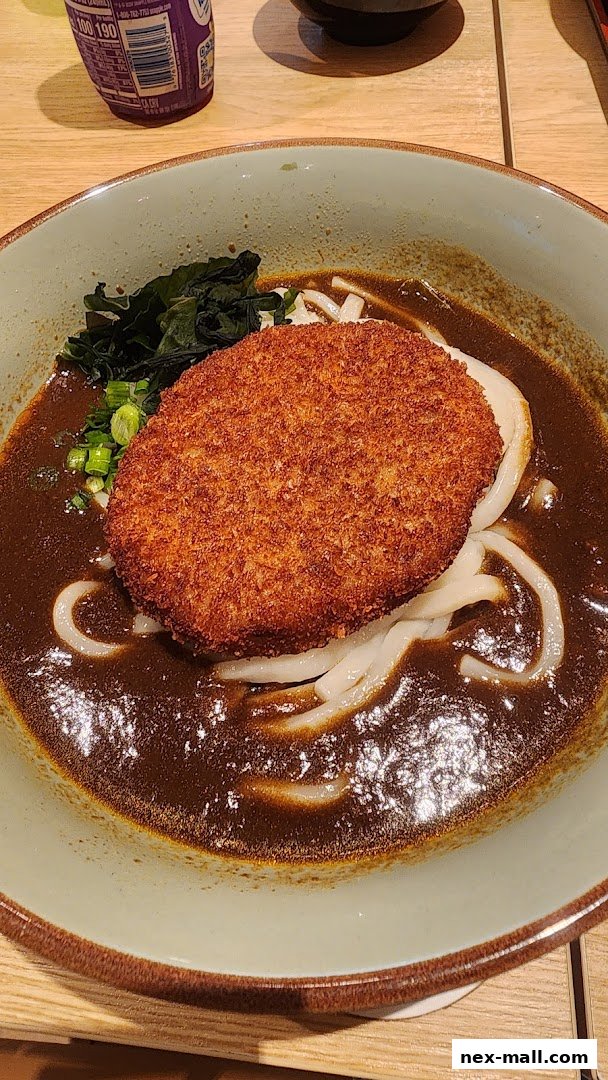 A bowl of udon noodles in curry broth topped with a crispy croquette.