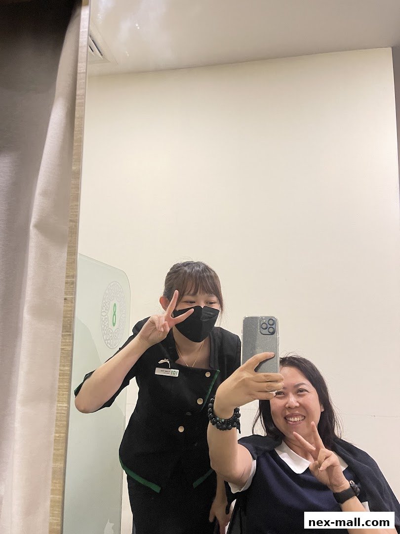 Two women smiling and posing for a selfie in a salon, one wearing a mask.
