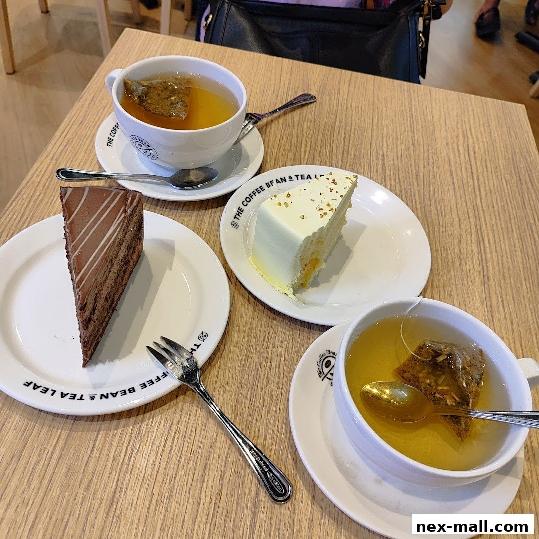 Two slices of cake and two cups of tea are arranged on a wooden table.