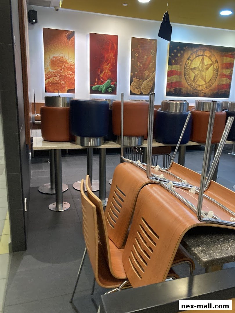 Interior of Texas Chicken NEX with stacked chairs and decorative wall art.